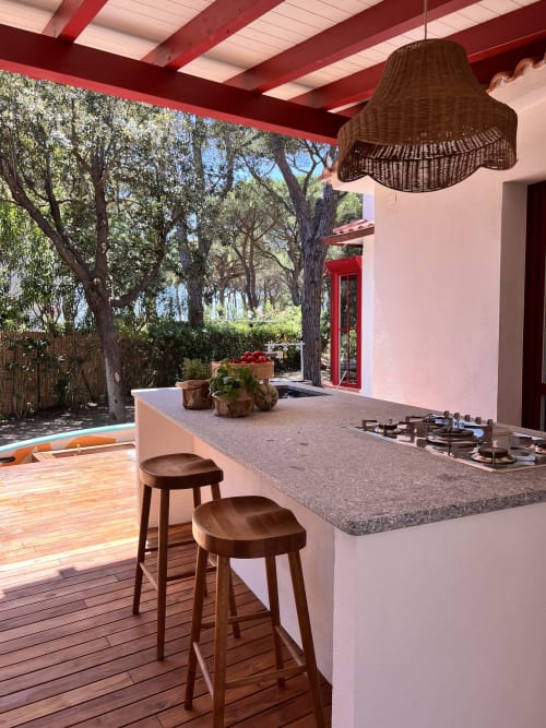 Open-air kitchen at Casa Rossa villa in Marina di Campo with island, gas stove, bar seating, and sea-view terrace under
