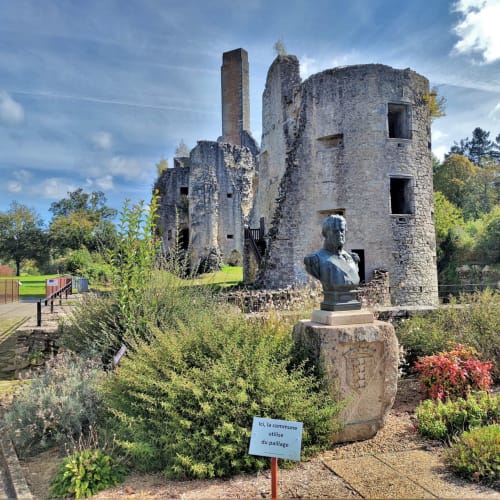 Tour de pierre en ruines avec buste sculptural au Domaine de Châlus-Chabrol à Châlus, France, entourée de jardins et de verdure