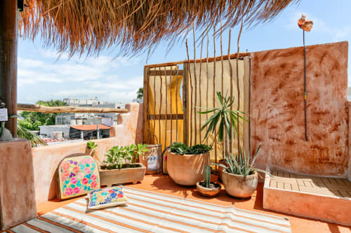 Colorful rooftop terrace at Isla Mujeres Realty with rustic decor, potted plants, striped rug, and city views