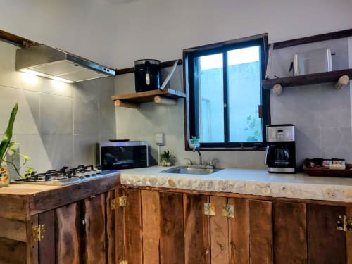 Modern kitchen in Isla Mujeres tiny house with stainless steel appliances, wooden cabinets, and garden view window