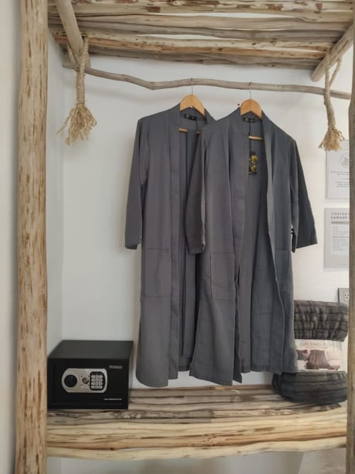 Charcoal cardigan sweaters hanging on wooden display rack in Isla Mujeres apartment closet with safe and decor