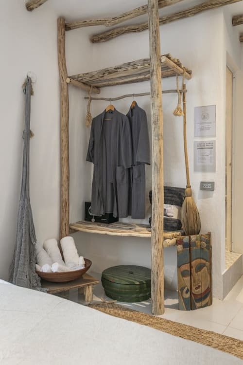 Rustic wooden wardrobe display with dark robes and woven baskets in Isla Mujeres rental apartment
