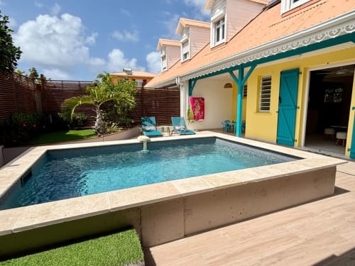 Piscine privée de la Villa Kay Lakansiel aux eaux turquoise, maison créole jaune, chaises longues et jardin tropical à Le Vauclin
