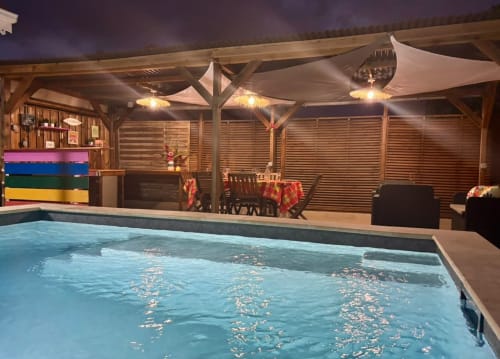 Piscine intérieure illuminée de la villa Kay Lakansiel au Vauclin avec pergola en bois, sièges détente et décor festif