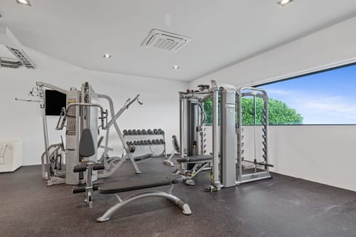 Modern gym at Isla Mujeres villa with cardio machines, weights, and sea view windows