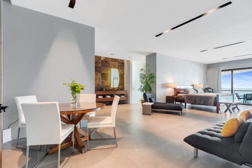 Modern villa living space at Isla Mujeres Realty with dining area, lounge seating, and sea view balcony overlooking the