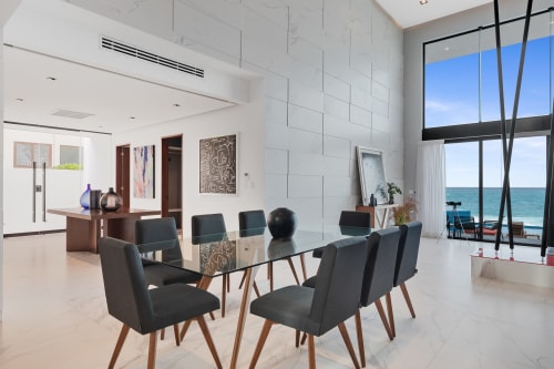 Modern beachfront villa dining area with glass table, black chairs, and ocean view at Isla Mujeres Realty