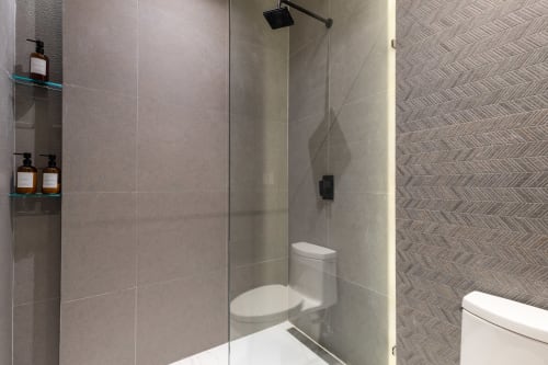 Modern bathroom in Villa E11even, Isla Mujeres with glass shower enclosure, white toilet, and tiled walls