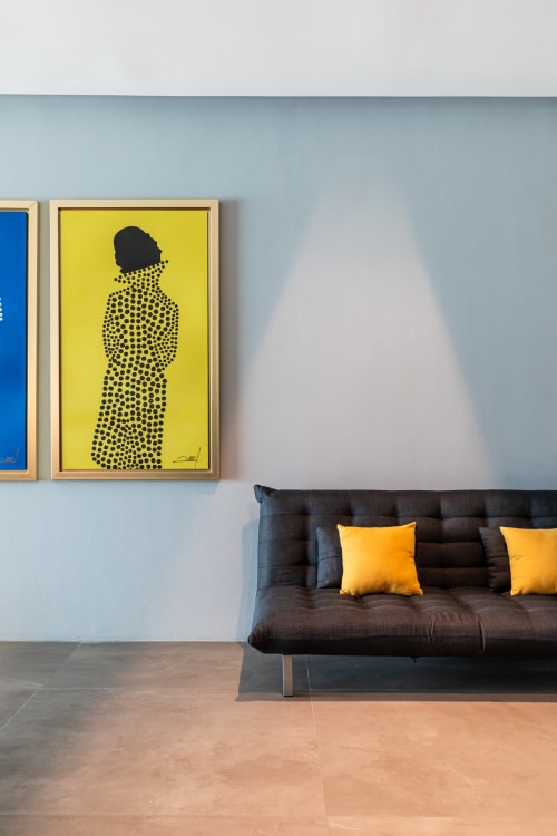 Modern villa interior at Isla Mujeres with black sofa, yellow pillows, and contemporary art on light blue wall