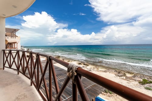 Oceanfront balcony with wooden railing overlooking turquoise waters and sandy beach at Casa Javi, Isla Mujeres