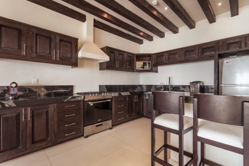 Modern kitchen with dark wood cabinetry, stainless steel appliances, and granite countertops in Casa Javi Ocean Front