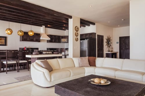Modern open-plan living room with cream sectional sofa, dark wood beams, and kitchen at Casa Javi, Isla Mujeres