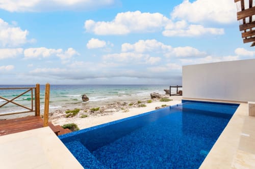 Oceanfront pool overlooking Caribbean beach at Casa Javi, Isla Mujeres Mexico with white modern architecture and clear blue