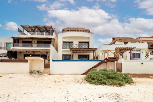 Beachfront cottage in Isla Mujeres with sandy oceanfront setting, white walls, wooden pergolas, and palm vegetation