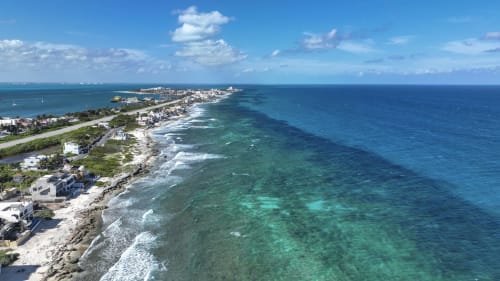 Aerial view of Casa Javi oceanfront cottage in Isla Mujeres with turquoise waters, sandy beach, and coastal development