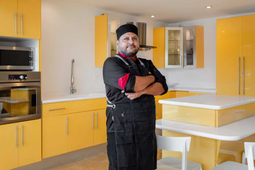 Professional chef in black apron posing in modern yellow kitchen at Villa Azul Maya Isla Mujeres