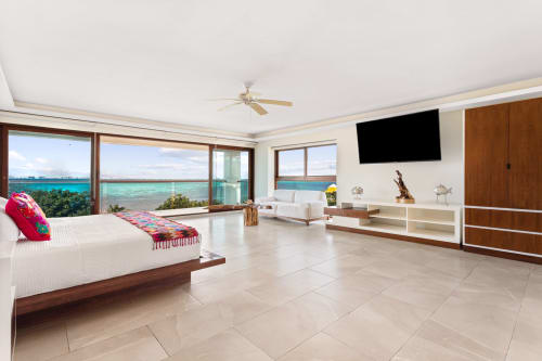 Spacious modern villa bedroom in Isla Mujeres with turquoise sea views, king bed, flat-screen TV, and oceanfront balcony