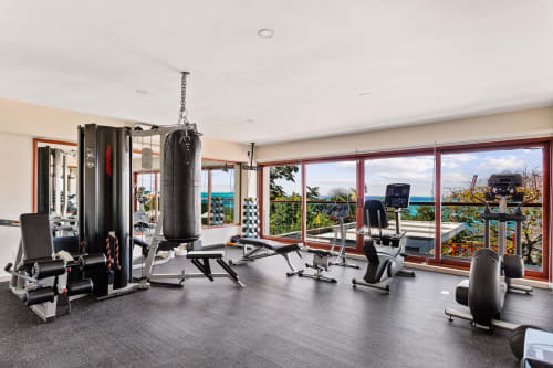 Modern gym with ocean views at Villa Azul Maya, Isla Mujeres. Equipment includes punching bag, weights, and cardio machines.