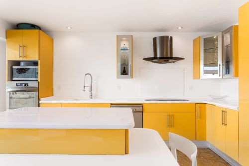 Modern kitchen with bright yellow cabinets, white counters, stainless steel appliances in Villa Azul Maya, Isla Mujeres
