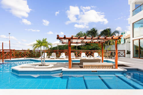 Luxury poolside terrace at Villa Azul Maya with wooden pergola, loungers, and turquoise water in Isla Mujeres