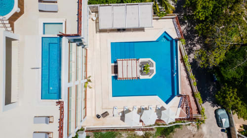 Aerial view of Villa Azul Maya pool in Isla Mujeres with bright blue swimming area, sun loungers, and tropical greenery