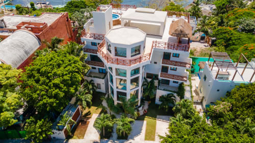 Aerial view of Villa Azul Maya, a white beachfront villa in Isla Mujeres with ocean views, surrounded by tropical greenery.