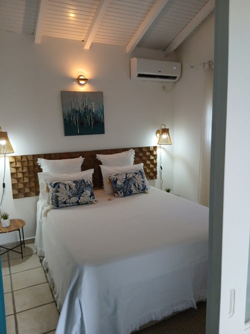 Modern bedroom at Le Nid De Bellemont cottage in Trois-Rivières with sea view, white bedding, patterned pillows, wooden