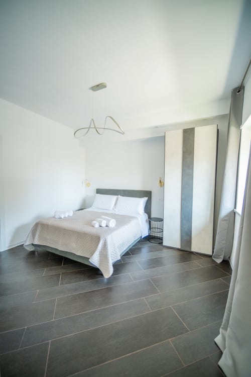 Camera moderna nell'appartamento Newhouse Argiro Deluxe a Bari, con letto matrimoniale, lampada a sospensione e pavimento in piastrelle scure