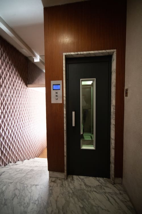 Ascensore moderno nella hall dell'Argiro Apartment Deluxe del Newhouse hotel di Bari, con pareti rivestite in legno