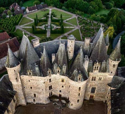 Vue aérienne du château de Châlus avec tours en pierre, remparts fortifiés et jardins à la française au Domaine de Châlus-Chabrol