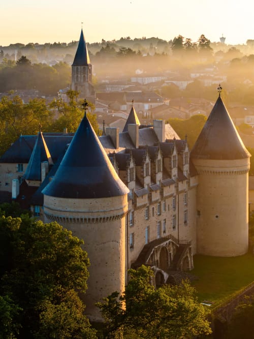 Château de Châlus avec ses tours de pierre et toits coniques à l'aube, niché dans la campagne française brumeu...