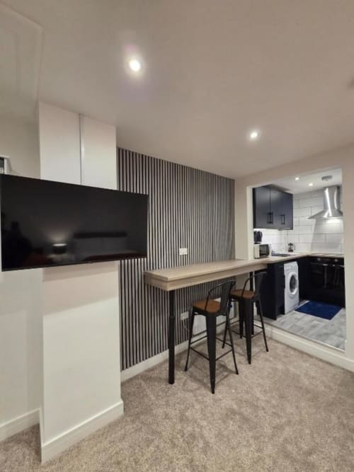 Modern studio apartment at The Courtyard by JS Apartments in Blackburn with kitchen, bar seating, and wall-mounted TV