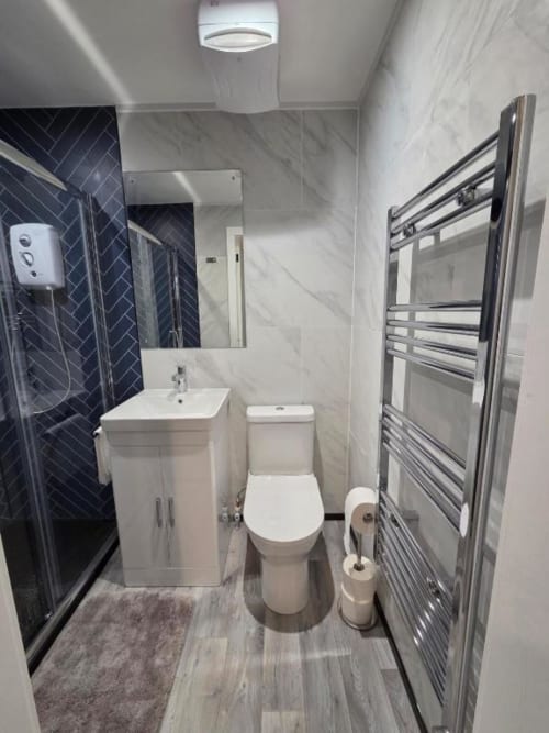 Modern bathroom at The Snug by JS Apartments in Blackburn with marble tiles, heated towel rail, and shower.