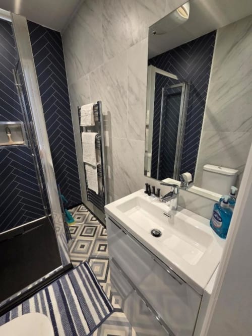 Modern bathroom in The Spacious Suite at The Courtyard by JS Apartments, Blackburn, featuring marble walls and black