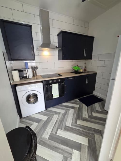 Modern kitchen in The Spacious Suite at The Courtyard by JS Apartments in Blackburn, featuring black cabinets and white