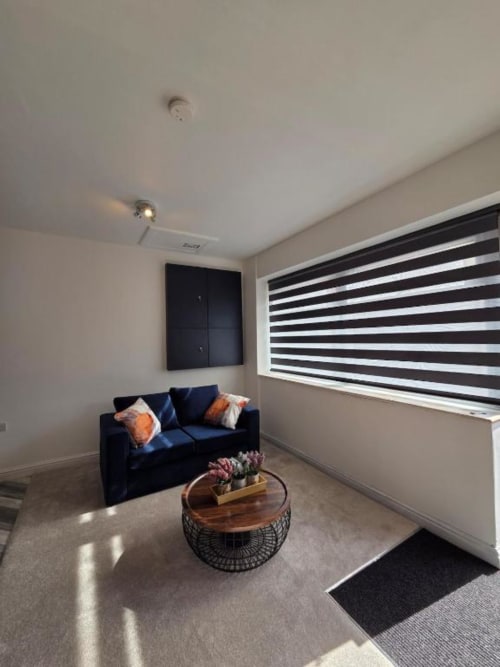 Modern living room at The Spacious Suite, The Courtyard by JS Apartments in Blackburn, featuring navy sofa with striped
