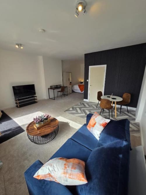 Spacious Suite at The Courtyard by JS Apartments in Blackburn - Modern living area with blue sofa, wooden coffee table, and