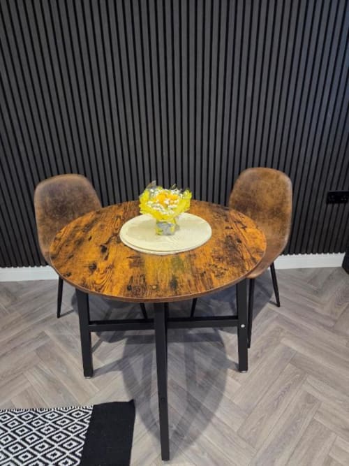 Round wooden dining table with yellow flower arrangement at The Courtyard by JS Apartments in Blackburn