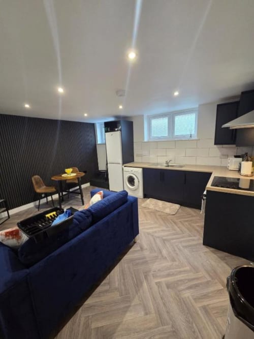 Modern open-plan apartment at The Courtyard by JS Apartments in Blackburn with blue sofa, black kitchen, dining area and