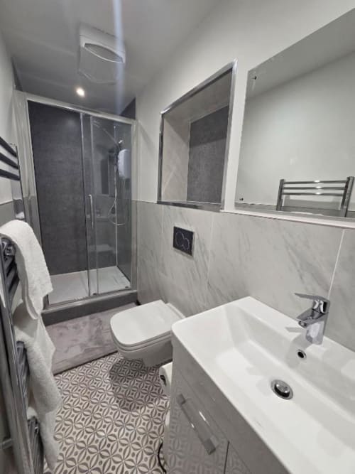 Modern bathroom at The Courtyard by JS Apartments Blackburn with shower enclosure, white vanity, and geometric floor tiles
