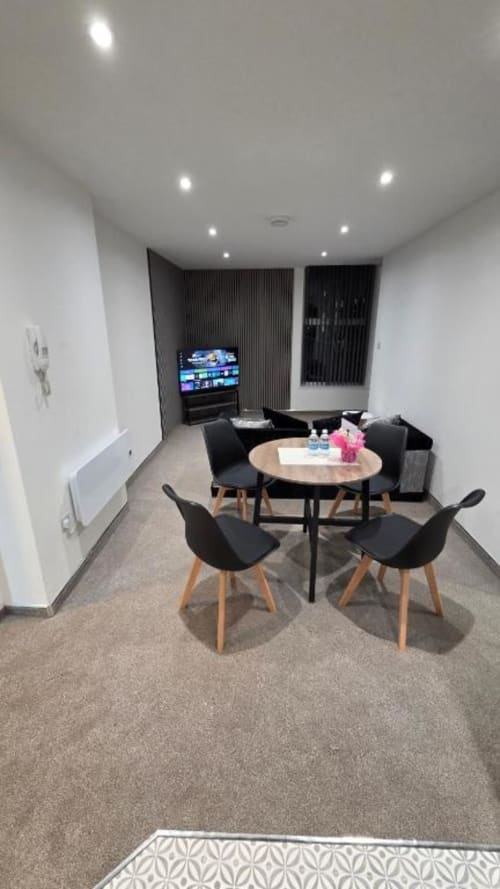 Modern family apartment lounge at The Courtyard by JS Apartments Blackburn with round table, black chairs, TV, and