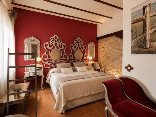 Chambre luxueuse au Complejo Turístico Retiro del Teatro avec tête de lit rouge ornementée, literie beige et décor rustique-moderne