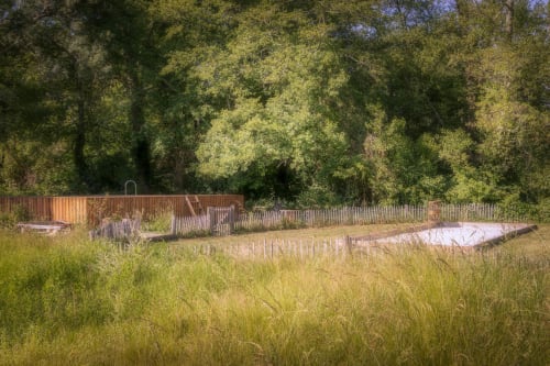 Rural garden at Domaine De Bafave B&B in Périssac, France with wooden deck, fencing, and forest backdrop