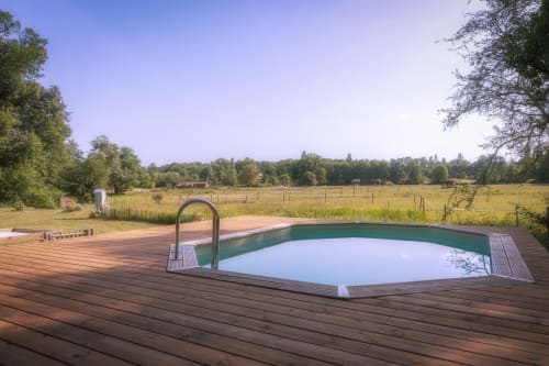 Domaine De Bafave pool and wooden deck overlooking pastoral fields in Périssac, France