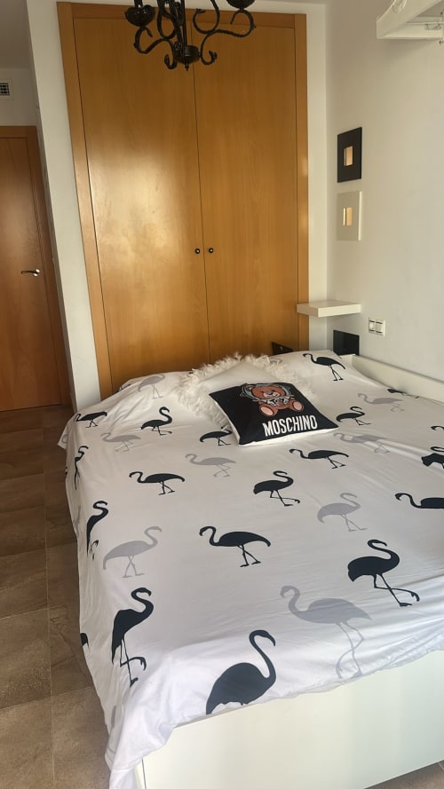 Dormitorio moderno con ropa de cama estampada de flamencos y armario de madera en el apartamento Sant Jordi con vistas a la montaña