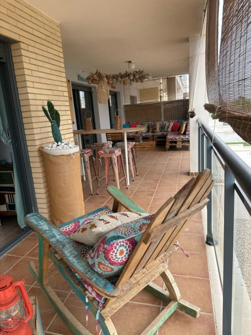 Acogedora terraza del apartamento Sant Jordi con muebles rústicos, cojines coloridos, cactus en maceta y vistas a las montañas