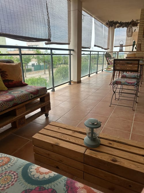 Soleada terraza de apartamento con vistas al golf en Sant Jordi con muebles de madera, asientos cómodos y vistas panorámicas de montaña