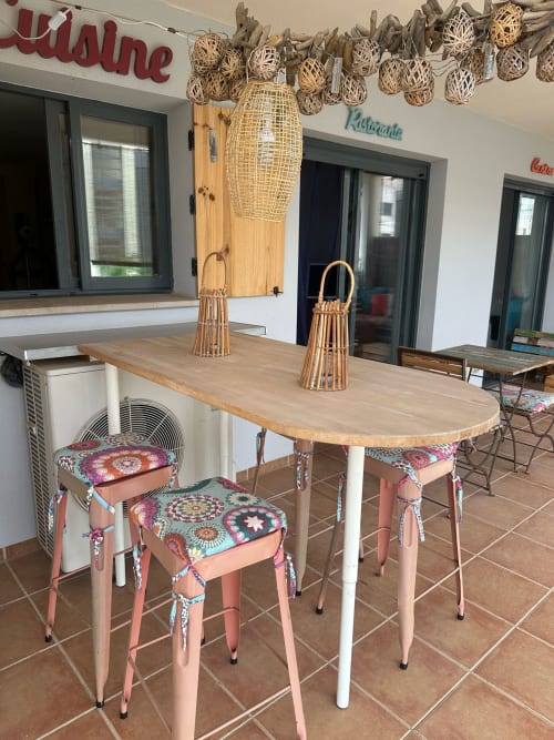 Terraza con comedor de madera, sillas acolchadas de colores y lámparas colgantes tejidas en el apartamento Golf Panorámica