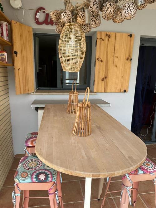 Comedor del apartamento Sant Jordi con mesa redonda de madera, sillas coral, lámparas colgantes tejidas y vistas a la montaña