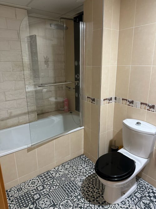 Baño moderno en el apartamento Sant Jordi con ducha, inodoro, azulejos con patrones en blanco y negro, y paredes de azulejos beige
